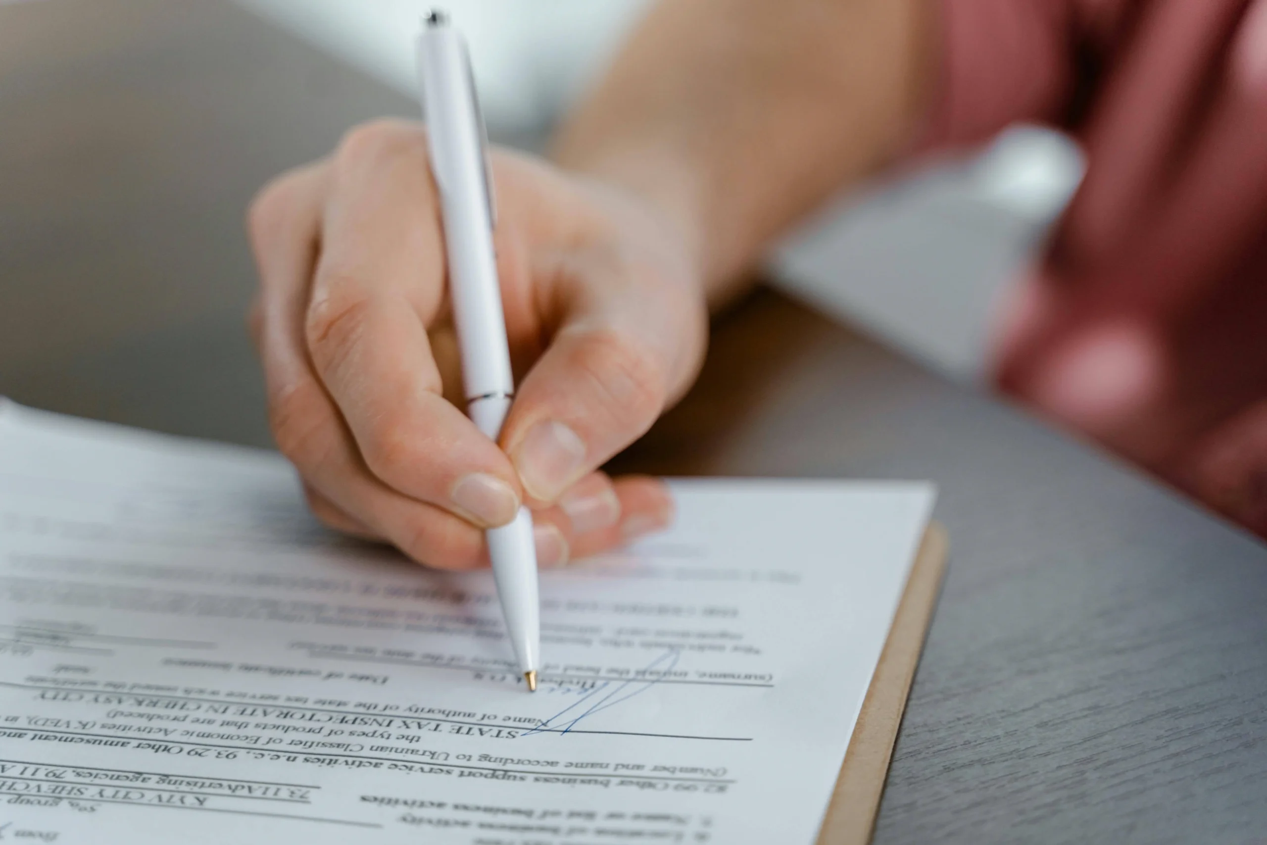 A person signing a document, representing how to set up a will.