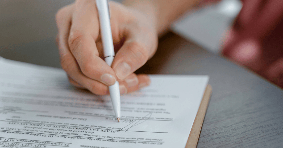 A person signing a document, representing how to set up a will.